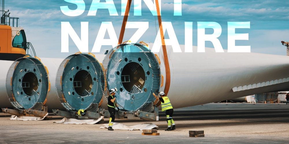 EOLE ST NAZ Prises de vues lors d'un suivi de chantier sur le port à St Nazaire sur le môle dédié aux éoliennes en mer. Deux hommes portant leurs E.P.I sont en train de poser les sangles à une pale d'éolienne. Travaux sur le port autonome