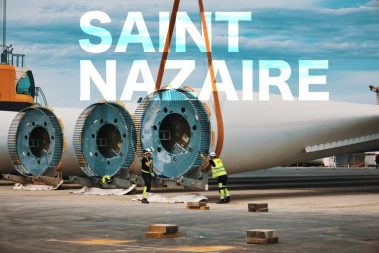 Prises de vues lors d'un suivi de chantier sur le port à St Nazaire sur le môle dédié aux éoliennes en mer. Deux hommes portant leurs E.P.I sont en train de poser les sangles à une pale d'éolienne. Travaux sur le port autonome
