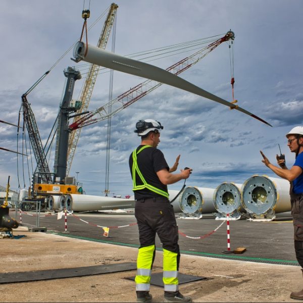 Coordinnation Deux hommes en charge de l'embarquement des pâles se coordonnent pour guider les engins de levage