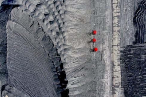 Trois ombres munies de parapluies rouges déambulent dans un décor lunaire et teinté de gris et de toutes ses nuances. Une ambiance à la Handmaid's Tale