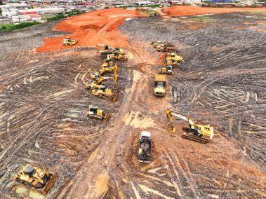 Des engins de terrassement sont alignés. Suite à une pluie tropicale, le chantier est à l'arrêt et les équipes en intempéries.