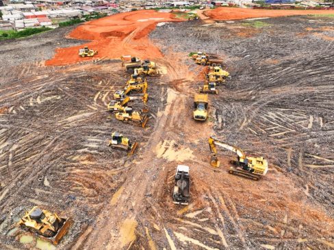 Des engins de terrassement sont alignés. Suite à une pluie tropicale, le chantier est à l'arrêt et les équipes en intempéries.