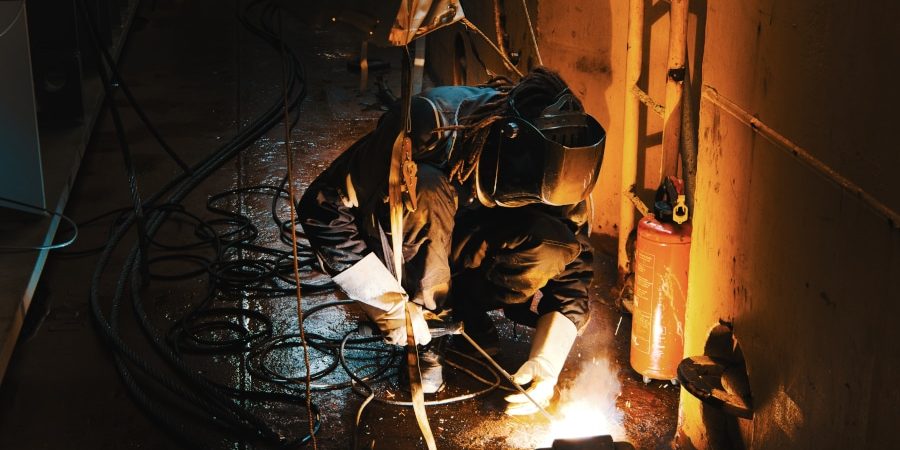 Un soudeur est en fond de cale afin d'améliorer et de renforcer un anneau de fixation. La photographie en milieu industriel un domaine d'excellence chez Olao