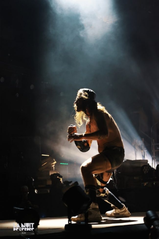 Frah du groupe Shaka Ponk en plein concert pendant leur tournée d'Adieux, lors de l'édition 2023 de La Nuit de l'Erdre. Prêt à bondir, à jouer avec la foule