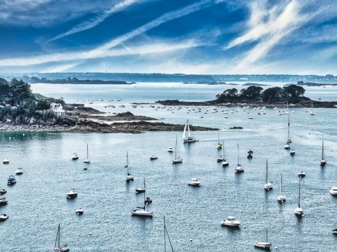 Un bateau rentre au port de Saint Briac en Bretagne. Ses voiles sont sorties et il cherche son corps-mort