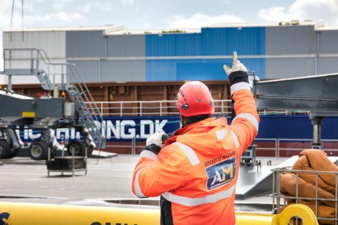 un docker du port de St Nazaire dirige des mains et à l'aide d'un talkie-walkie un déchargement de marchandises sur le port autonome de Saint Nazaire. Des opérations quotidiennes de travaux portuaires.