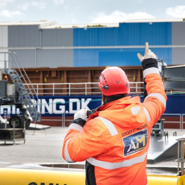 Docker sur le port de St Nazaire un docker du port de St Nazaire dirige des mains et à l'aide d'un talkie-walkie un déchargement de marchandises sur le port autonome de Saint Nazaire. Des opérations quotidiennes de travaux portuaires.
