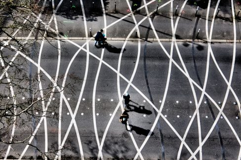 Des enfants à trottinette traversent à l'aide de leurs parents un passage piéton. ce passage piéton est particulier car il s'agit des célèbres spaghettis sur le boulevard Léon Bureau à Nantes. Ils vont bientôt disparaitre avec l'arrivée des travaux. C'est photo est donc déjà un souvenir lointain.