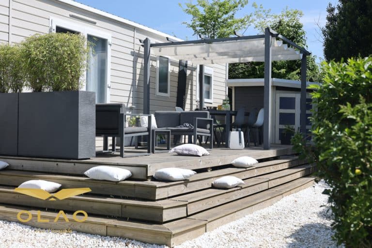 Un Mobile-home doté d'une pergola. Une jolie terrasse avec des marches suffisamment larges pour que l'on puisse s'y assoir.