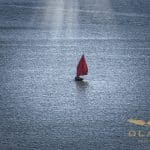 Un sinagot, le fameux bateau de séné dans le Morbihan. Il se caractérise par sa voile rouge. Un rayon de soleil vient frapper ce frêle esquif au milieu du Golfe du Morbihan.