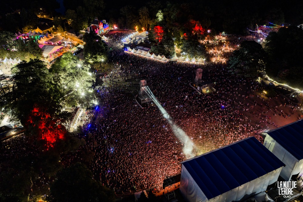 Vue d'ensemble par drone du site de La Nuit de l'Erdre 2026 la nuit à Port-Mulon : scènes, arbres illuminés et festivaliers