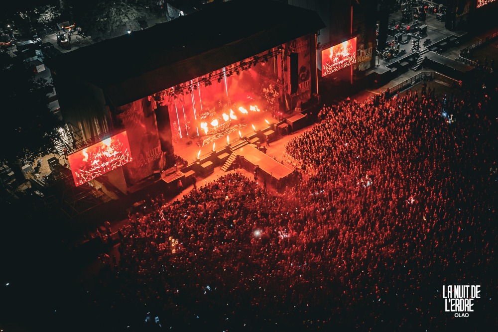 Grande scène de La Nuit de l'Erdre 2026 vue par drone pendant un concert, jets de flammes et public éclairé en rouge